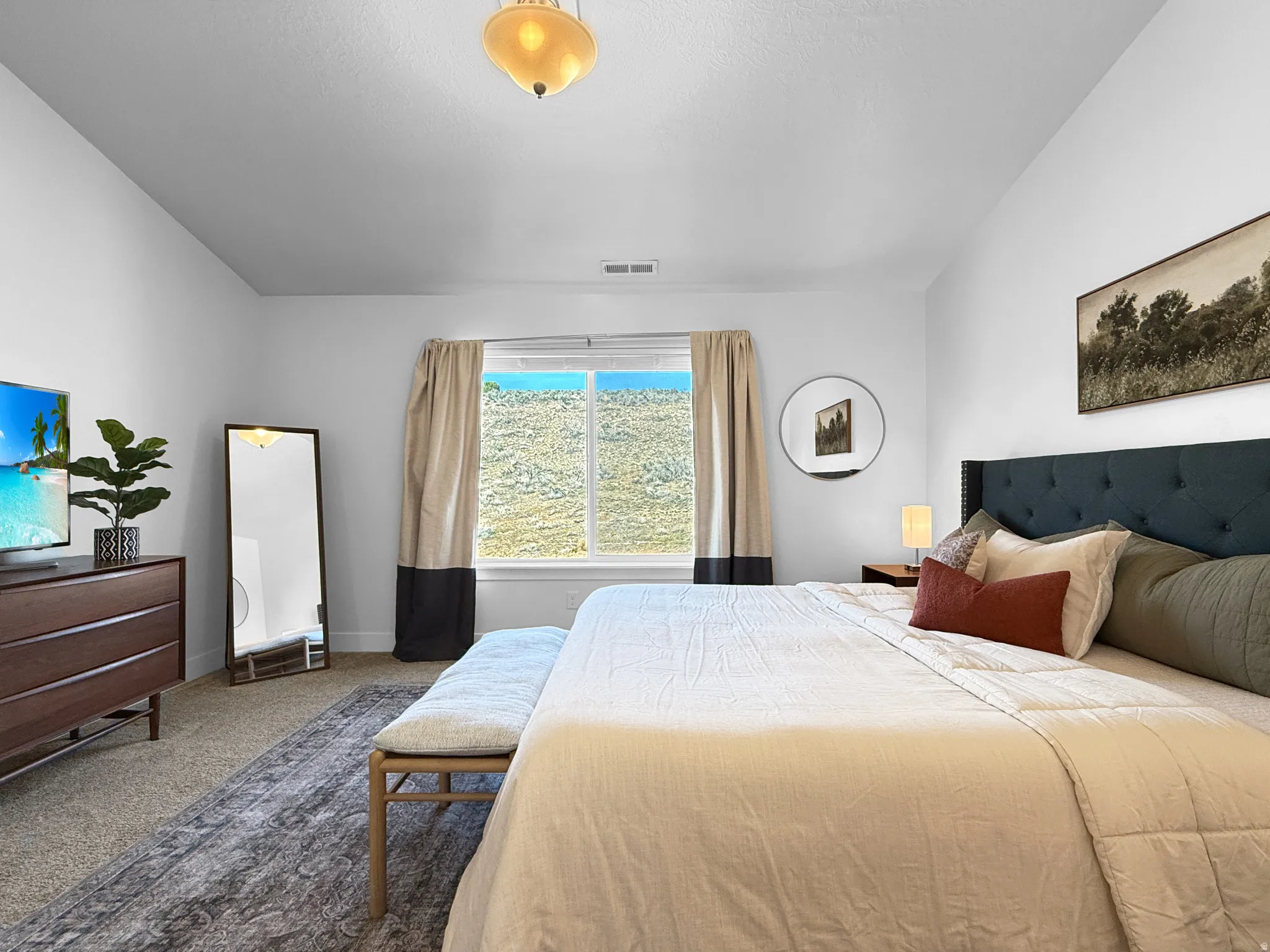 Spacious bedroom featuring vaulted ceilings, a large window with two-tone drapery, and neutral carpeting