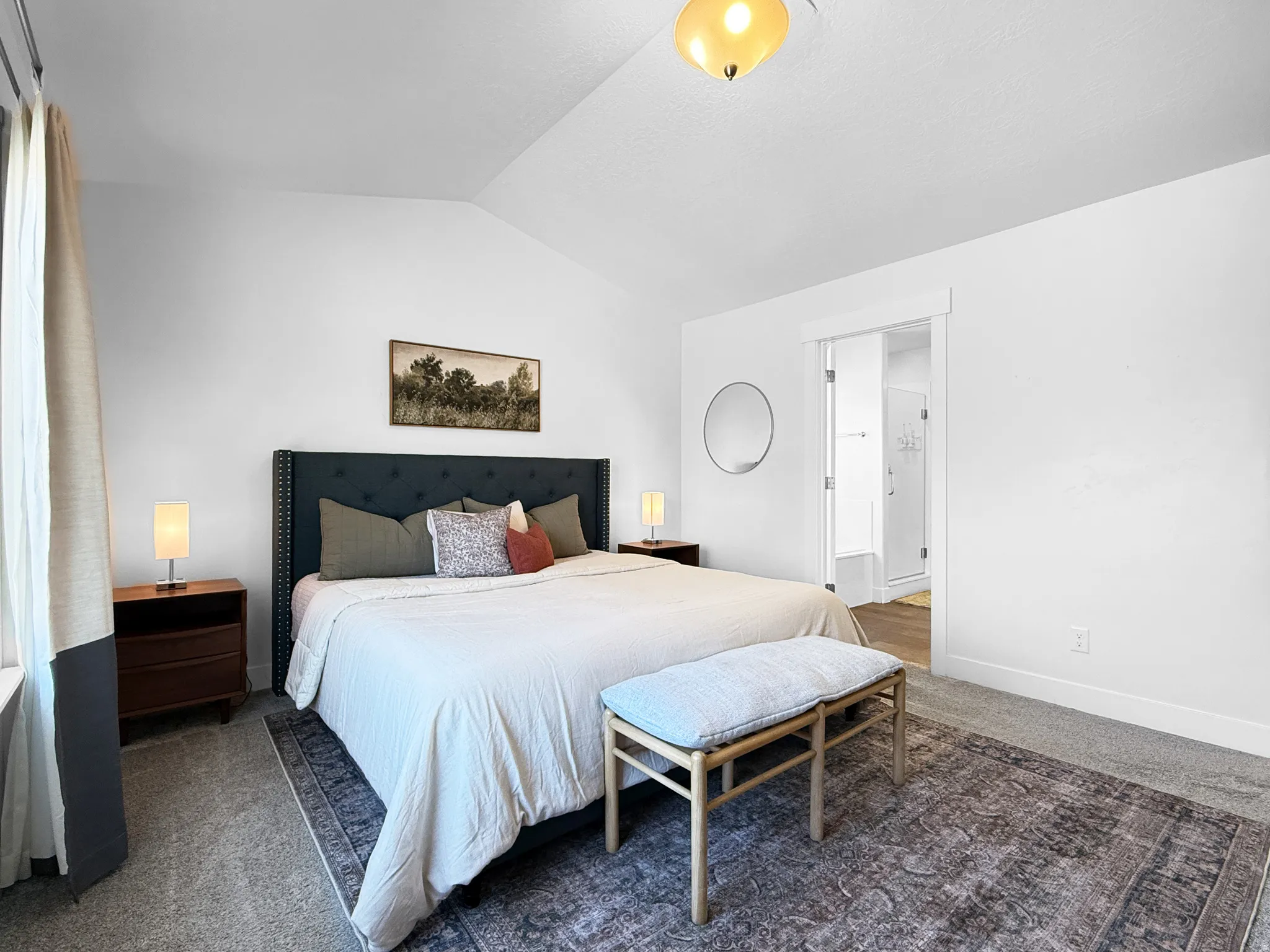 Spacious bedroom featuring vaulted ceilings, a large window with curtain rod, neutral wall finishes, and carpet flooring