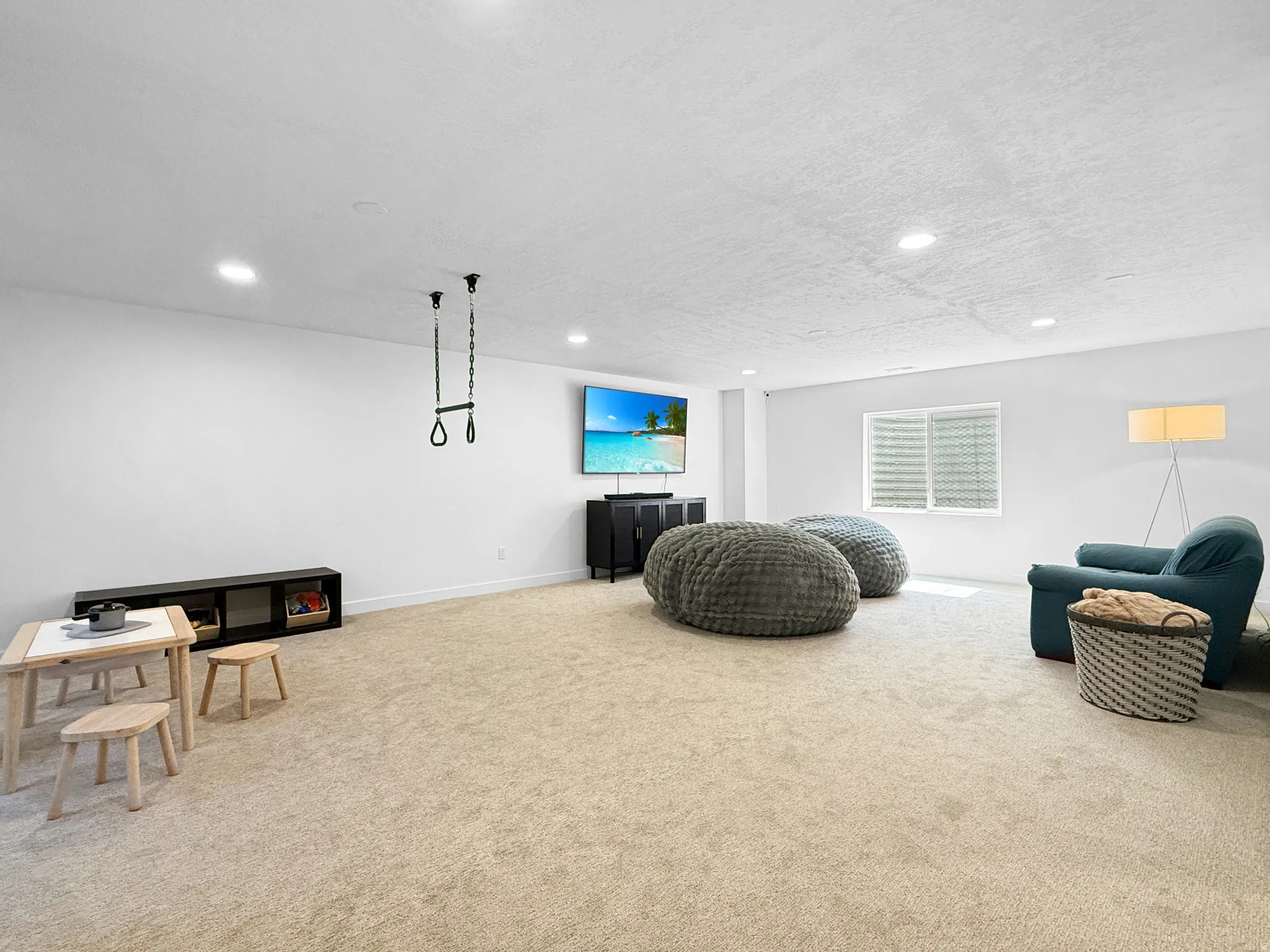 Spacious room featuring neutral carpeting, recessed lighting, and a window with horizontal blinds