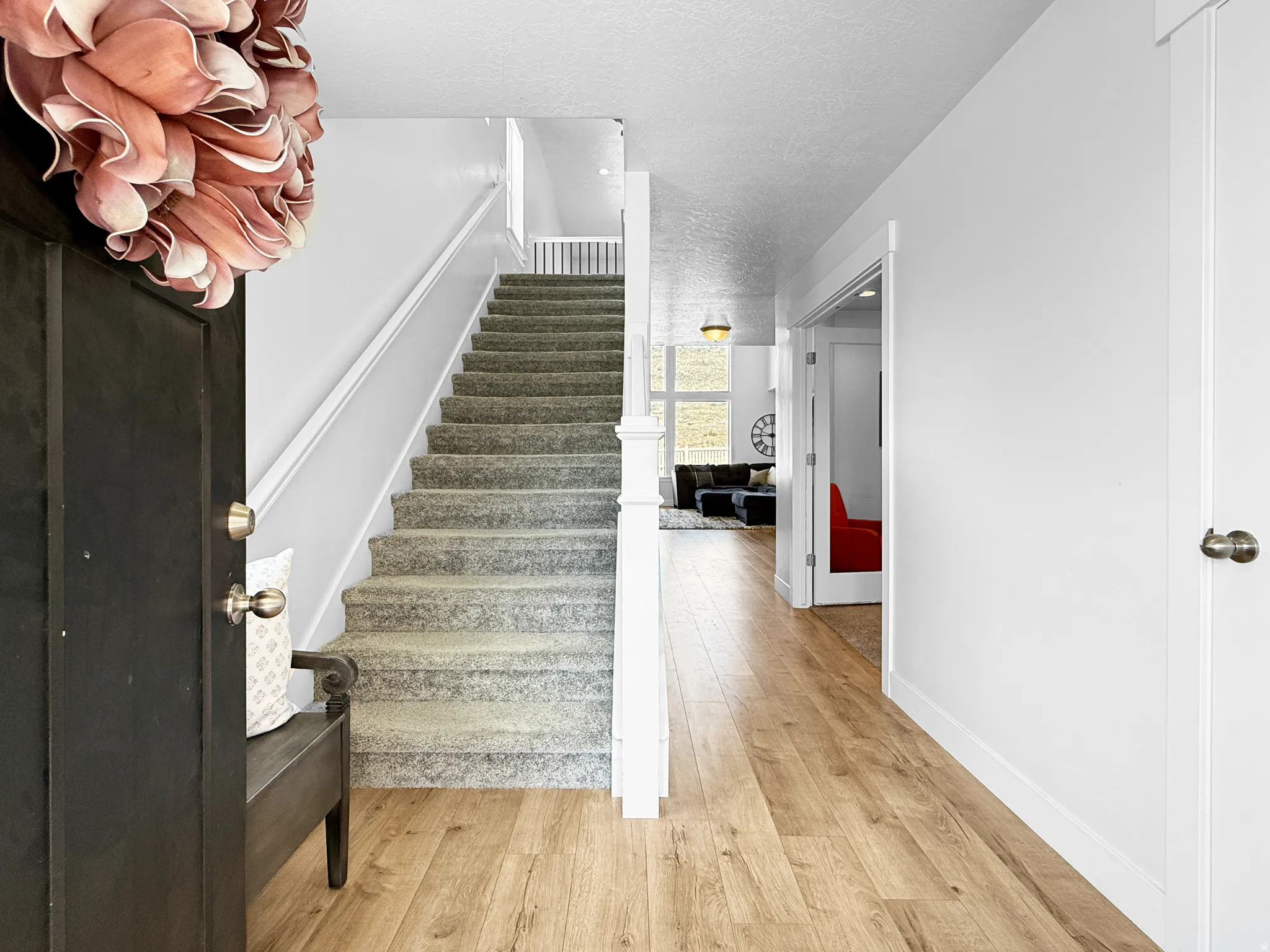 Entryway featuring wood-finish flooring, a carpeted staircase with white railings, and white interior doors