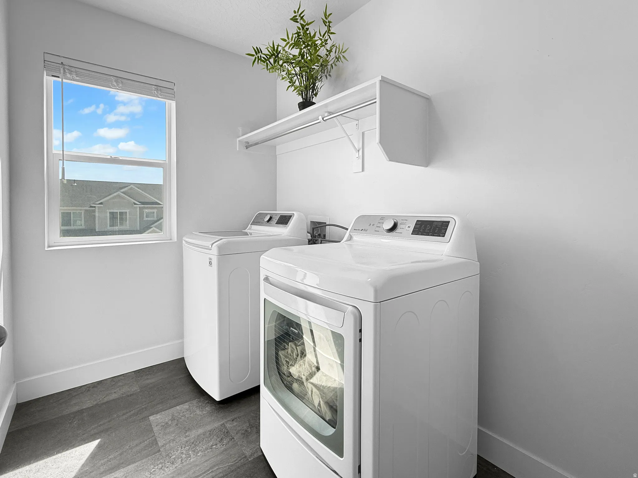 Dedicated laundry area featuring a window, built-in shelving, white walls, and wood-finish flooring