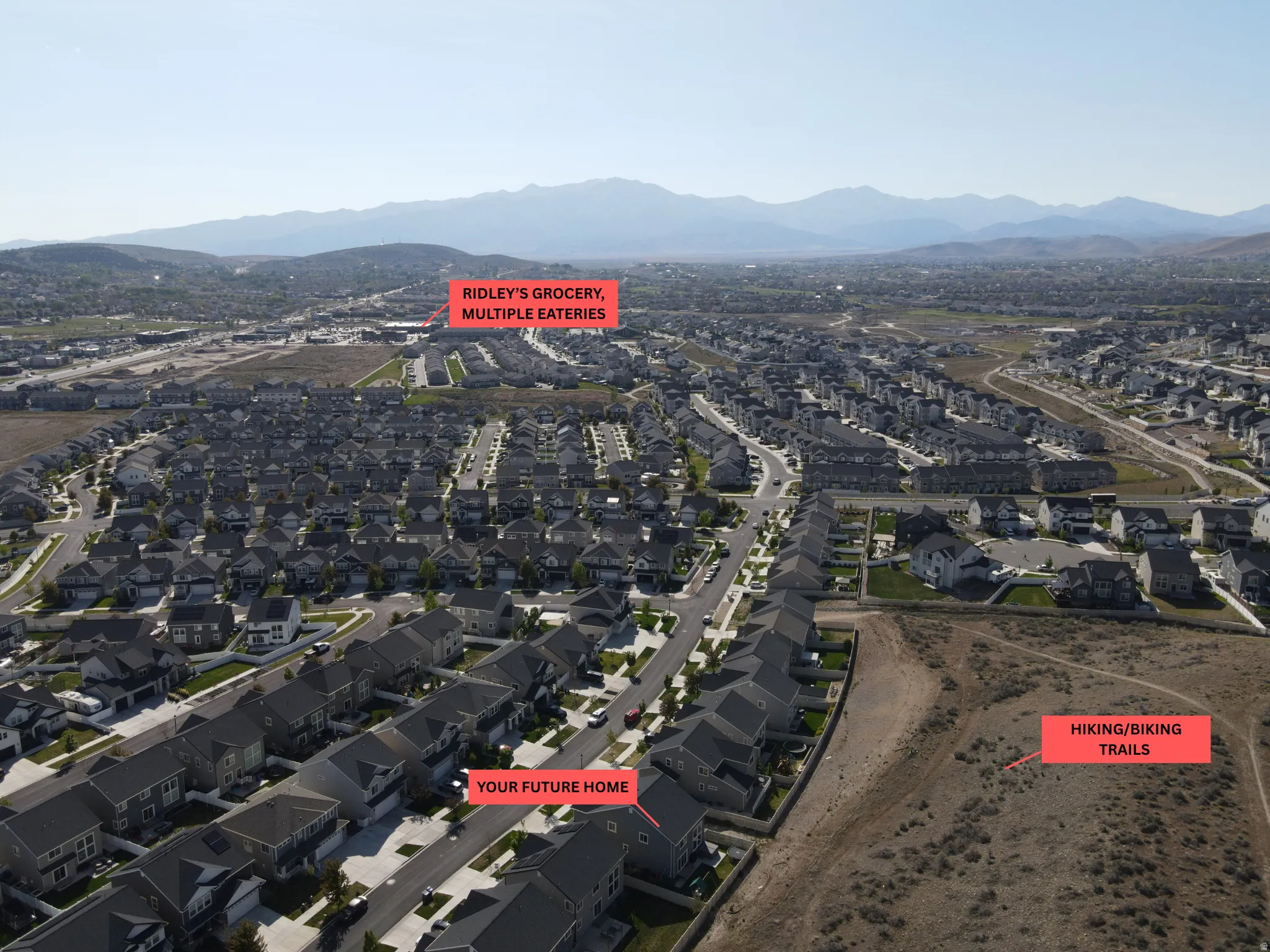 Residential community with numerous single-family homes, mountain backdrop, and expansive open spaces
