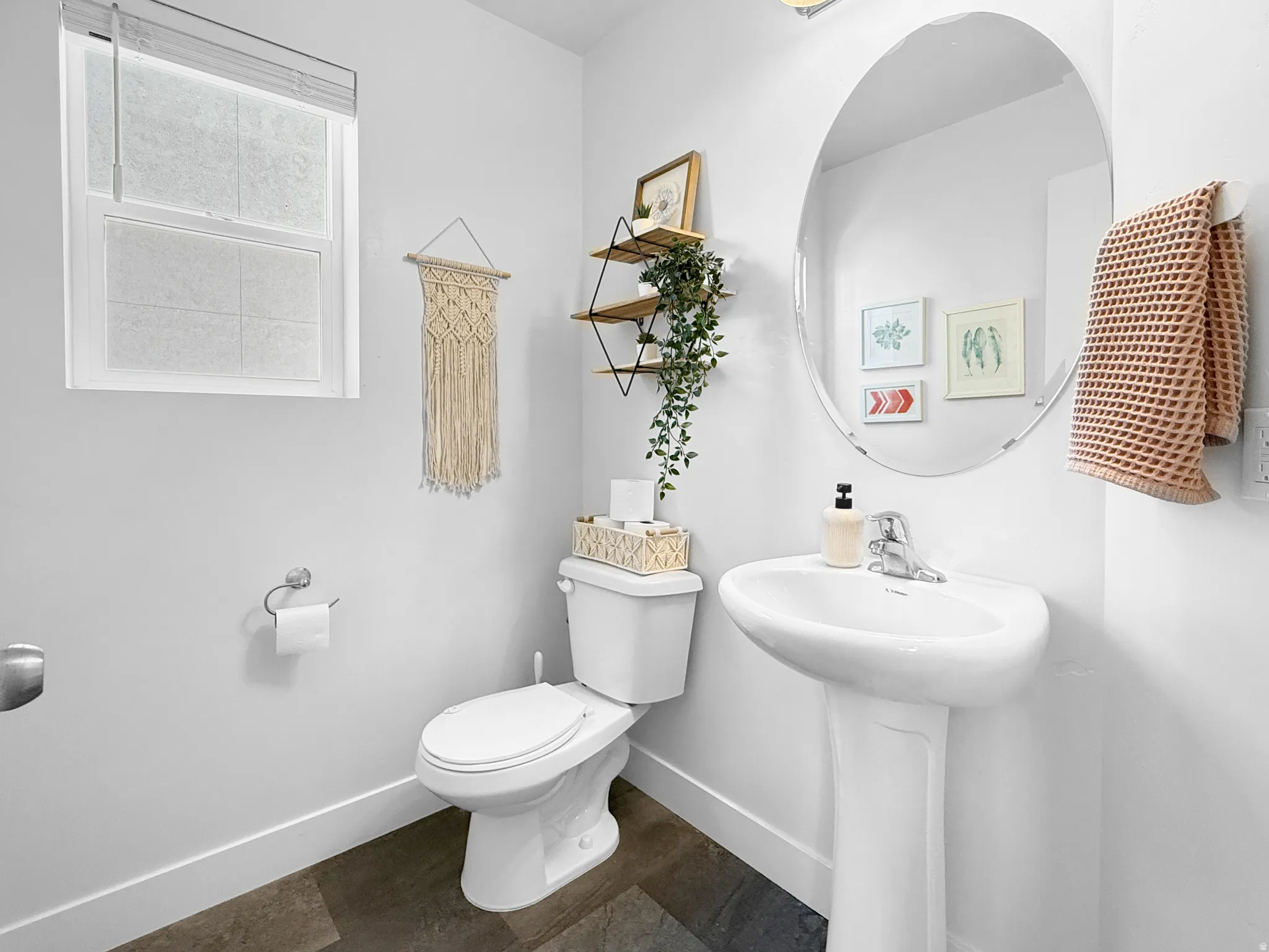 Pedestal sink with chrome faucet, complemented by a large oval frameless mirror