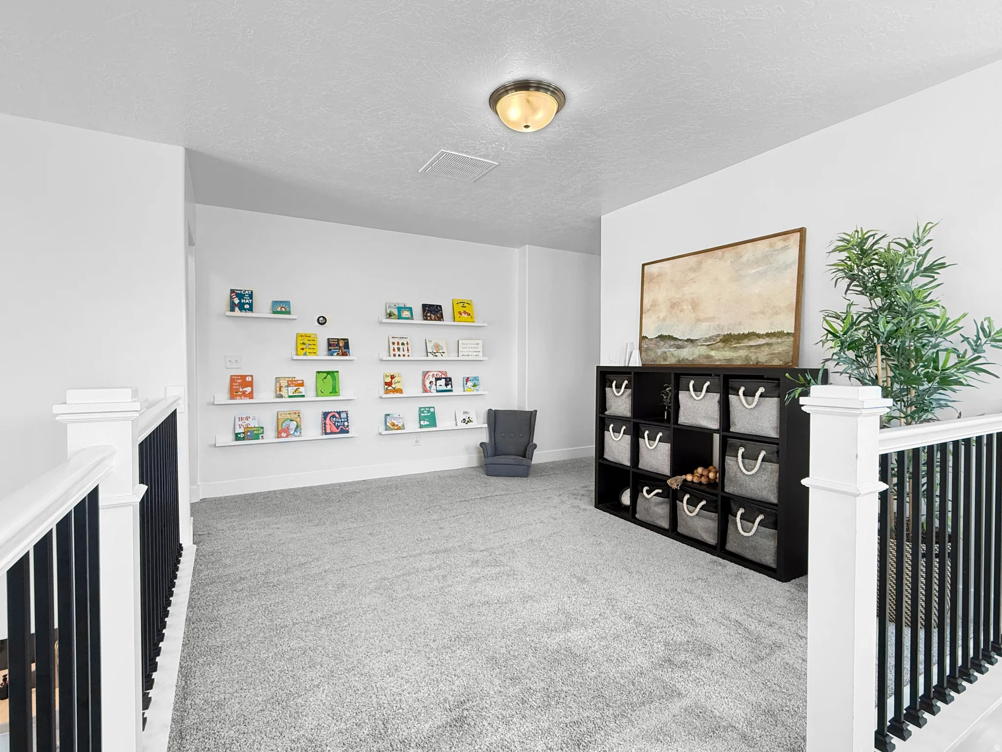 Carpeted loft area featuring a white railing with black spindles, recessed built-in shelving, and a flush mount ceiling light