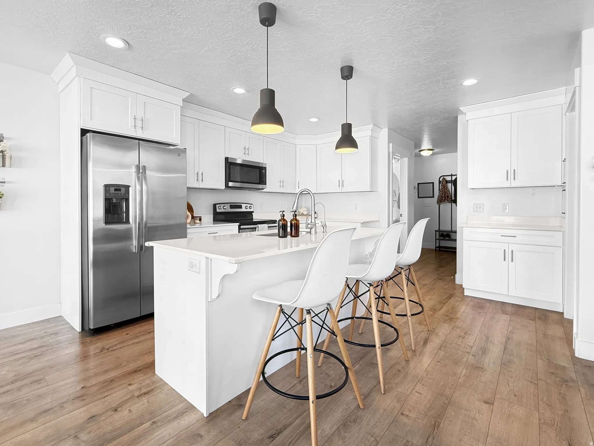 Contemporary kitchen featuring white cabinetry, stainless steel appliances, and a central island with countertop seating