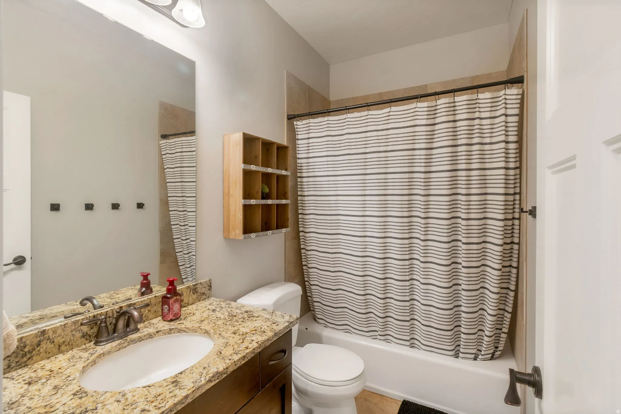 Bathroom featuring a single vanity with a patterned countertop, a white undermount sink, and a bronze-finish faucet