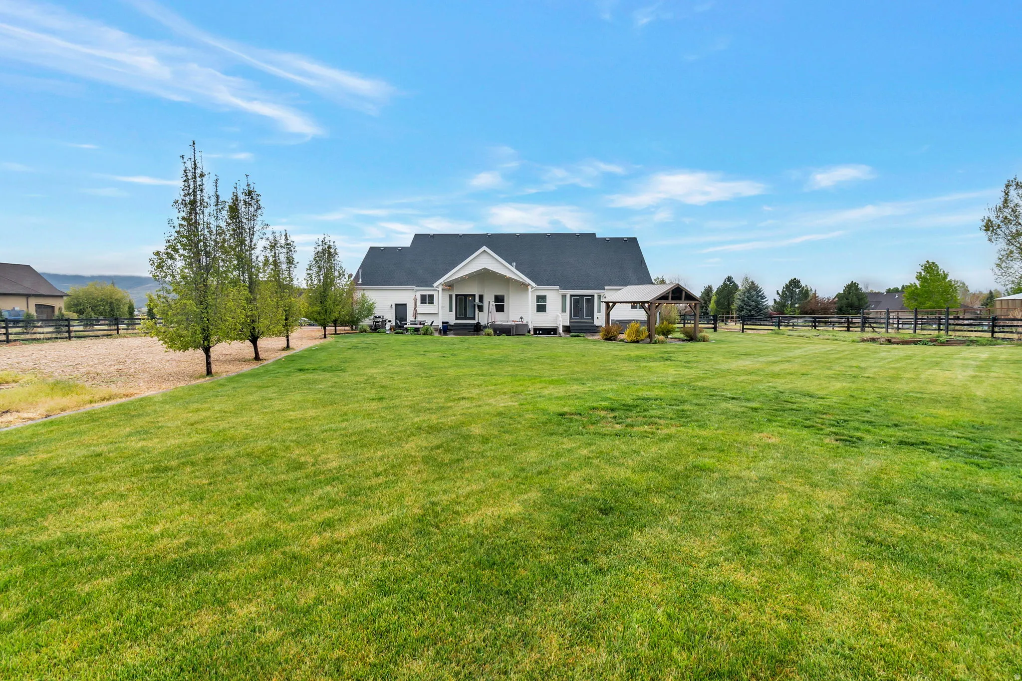 Expansive green lawn surrounds a white exterior residence with a dark roof