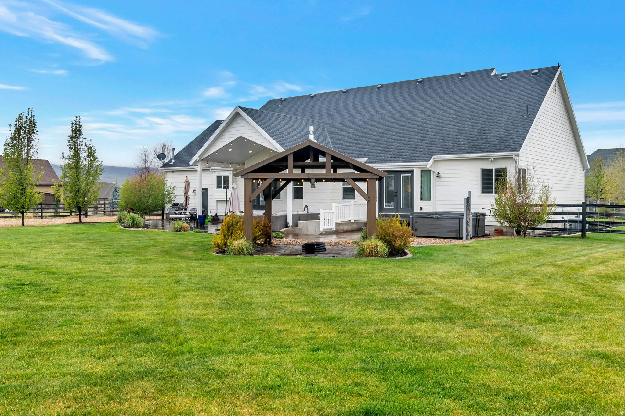 White siding exterior with a dark shingle roof and covered patio
