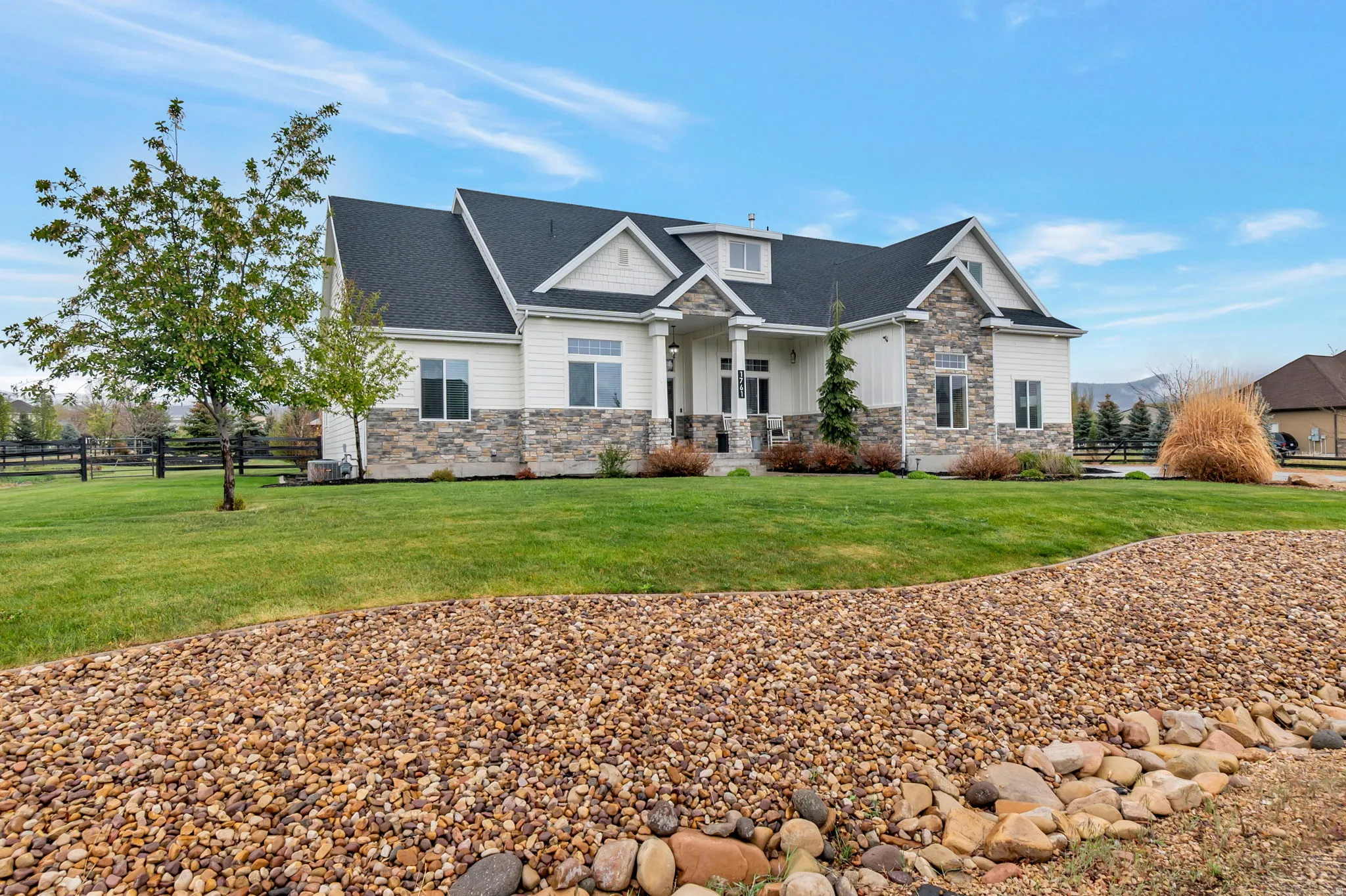 Traditional-style residence featuring a prominent front facade with white siding and stone accents