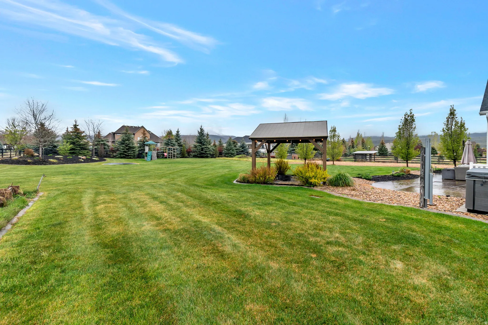 Expansive green lawn with mature trees and a dedicated patio area