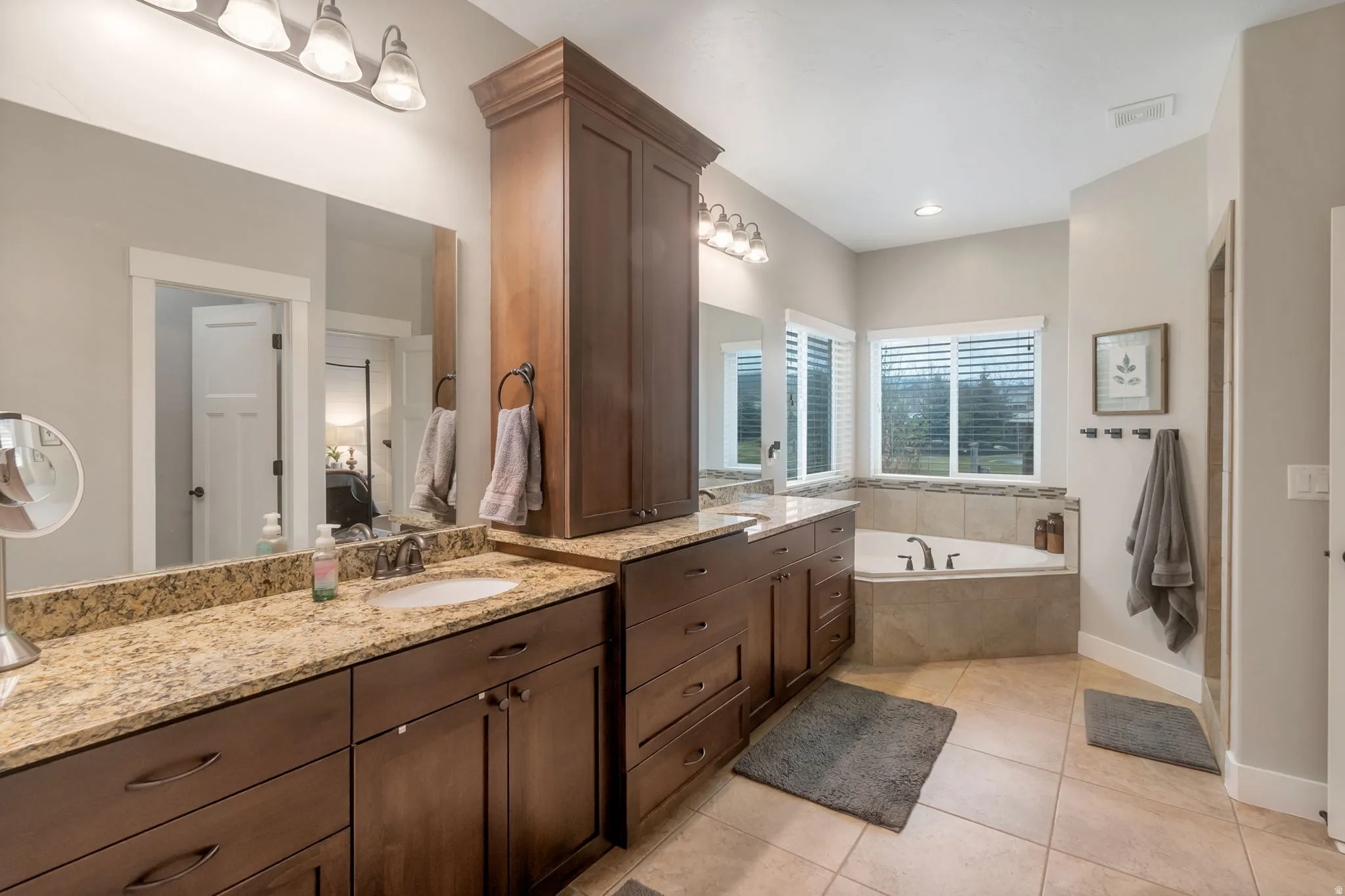 Dual sink vanity featuring granite countertops and wood cabinetry