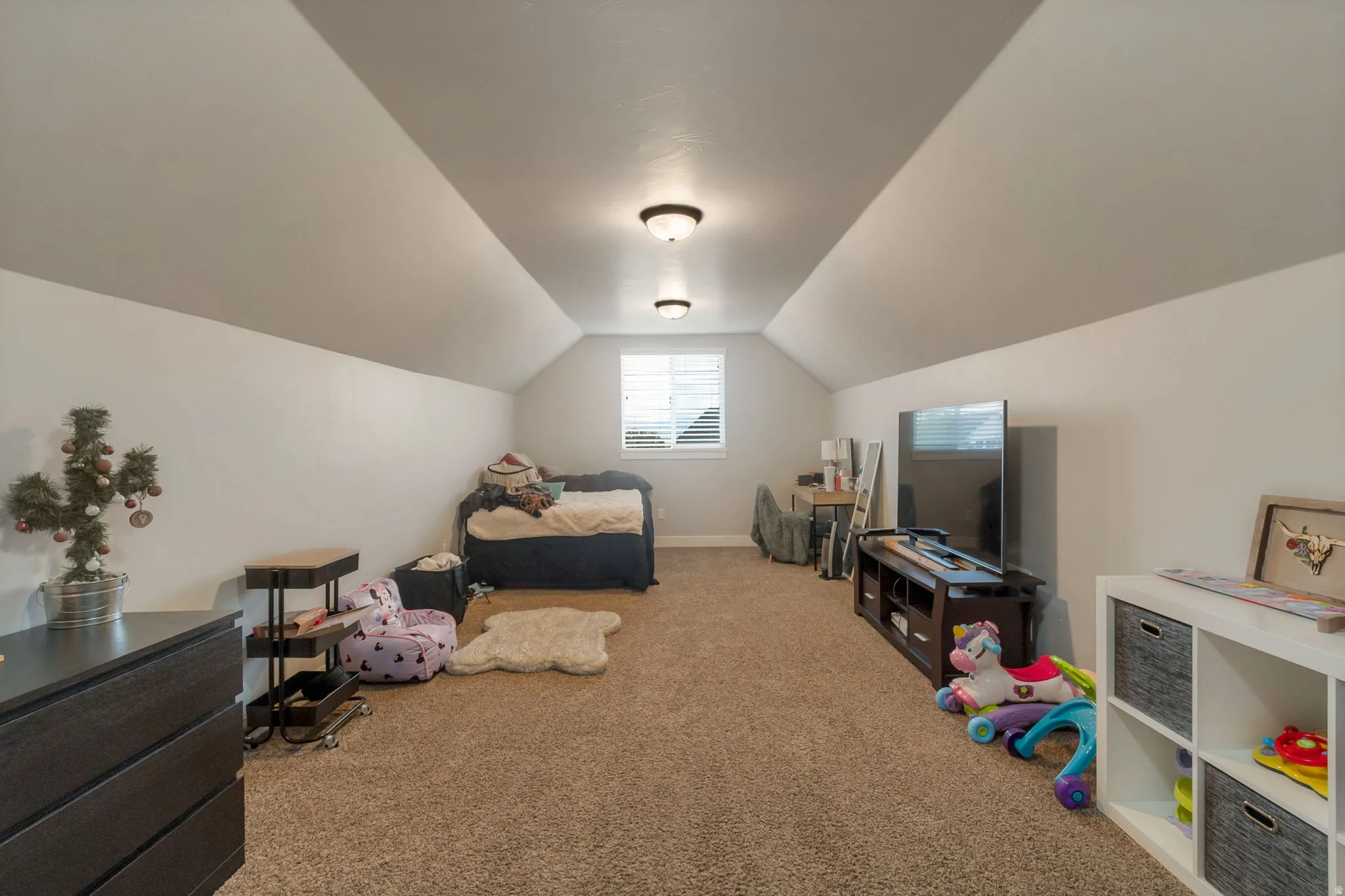 Carpeted room with sloped ceilings and recessed lighting