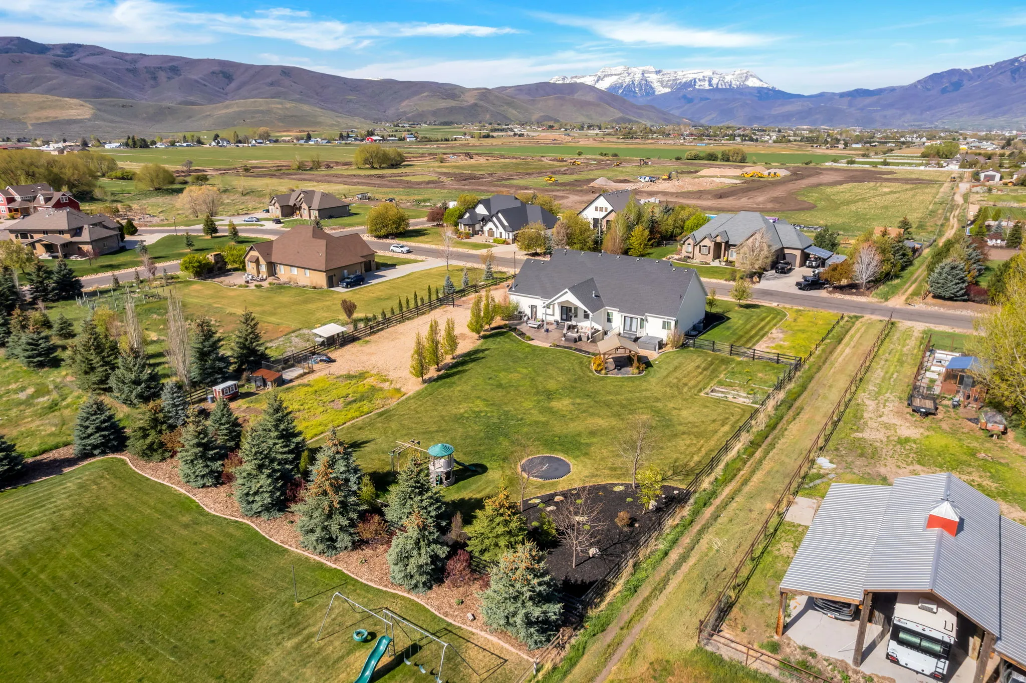 Expansive property featuring a large manicured lawn, established landscaping, and a spacious rear patio with pergola