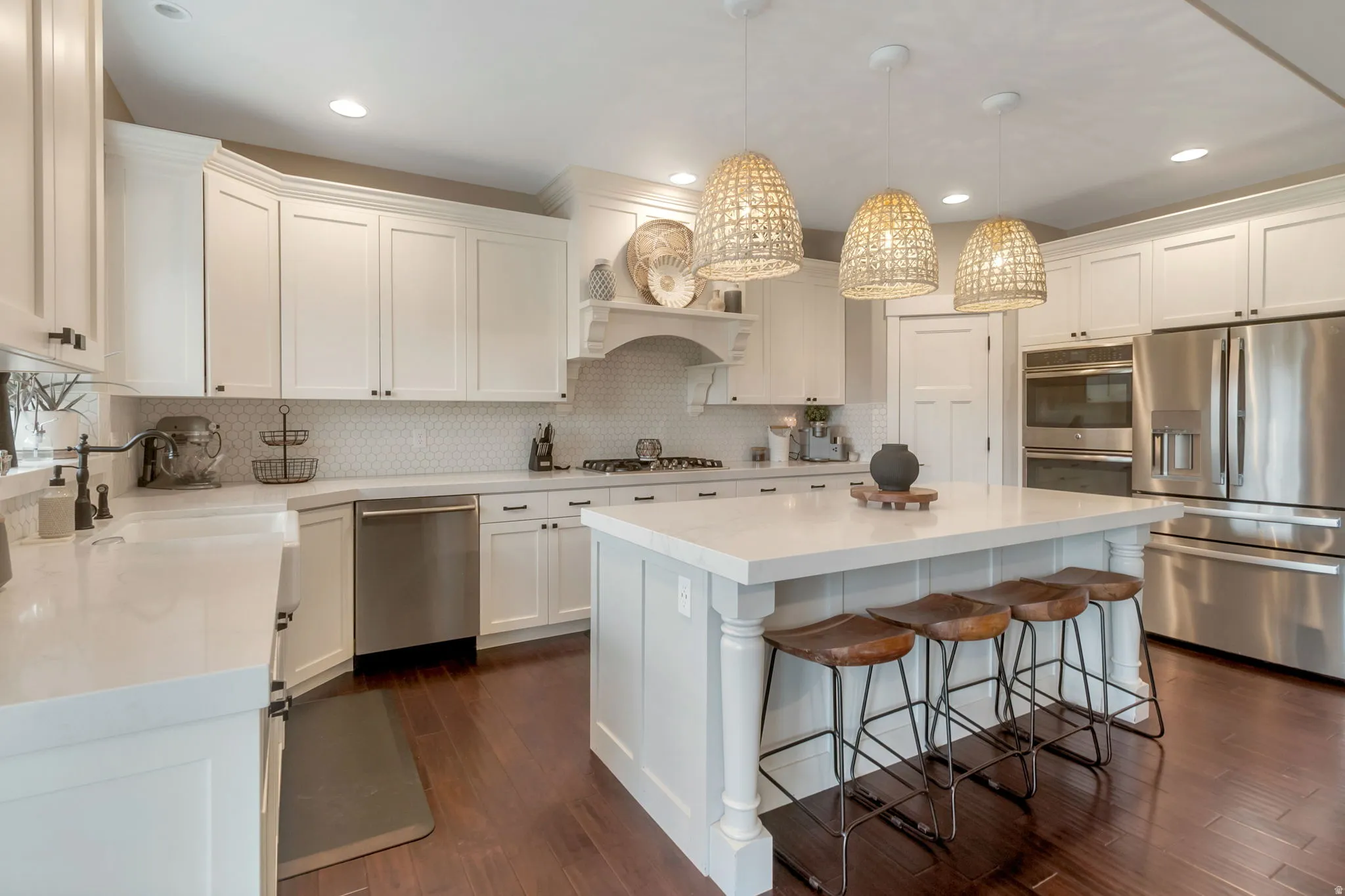 Spacious kitchen featuring an expansive central island with seating, white shaker cabinetry, stainless steel appliances, and wood-finish flooring