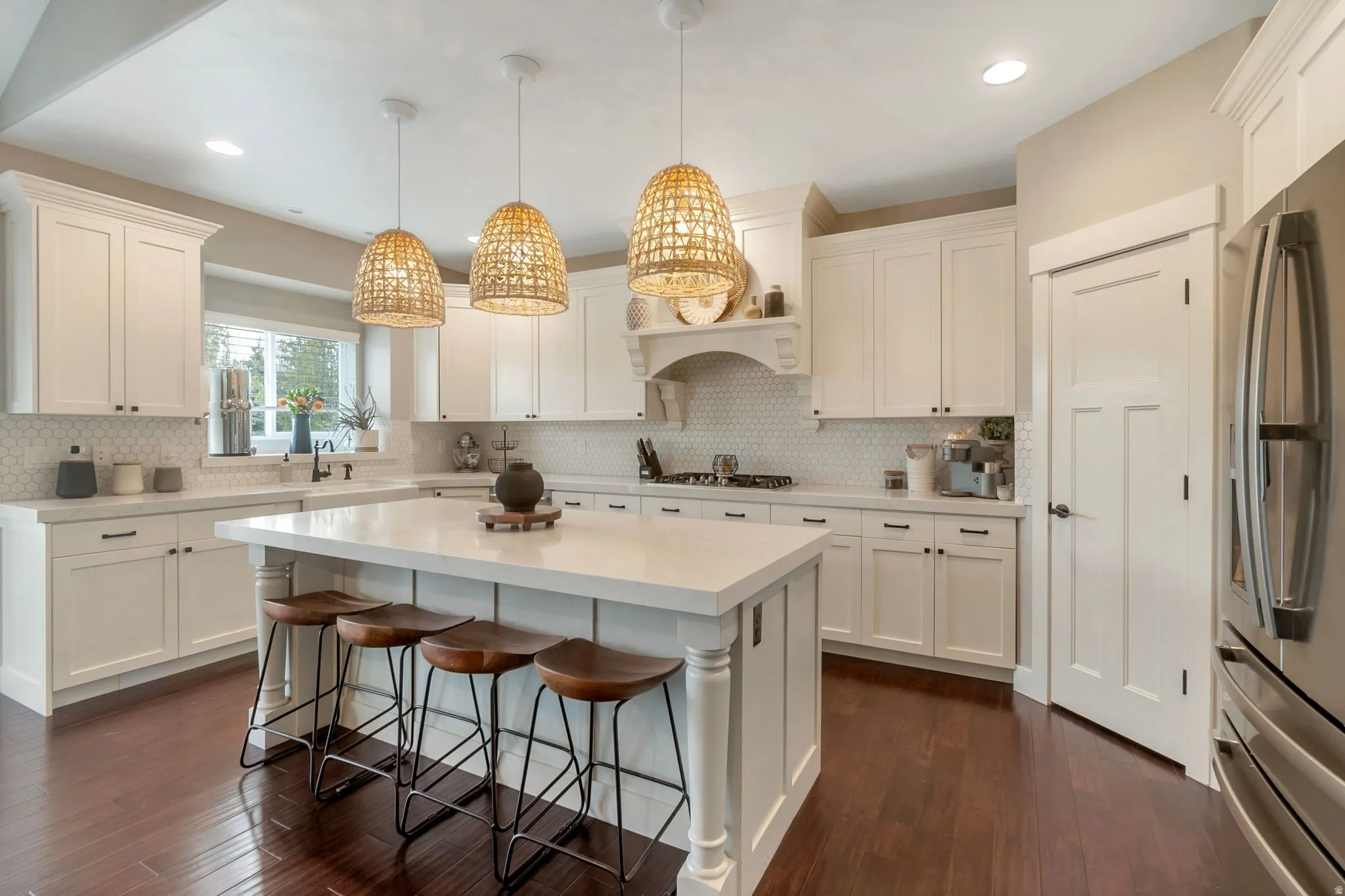 Spacious kitchen featuring an expansive center island, white cabinetry, light countertops, honeycomb tile backsplash, and dark wood-finish flooring