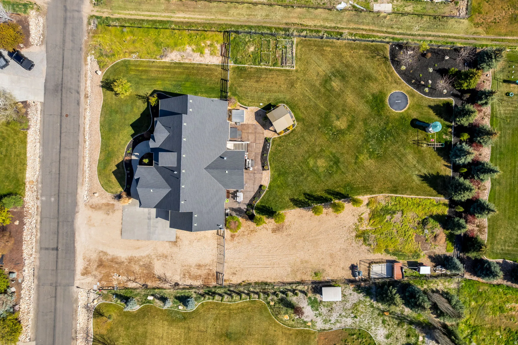 Expansive property featuring a dark-shingled roofline, verdant lawn areas, and mature trees