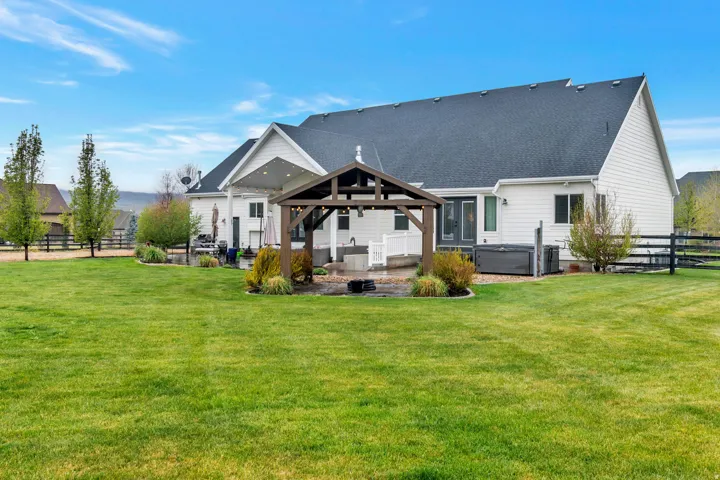 White siding exterior with a dark shingle roof and covered patio