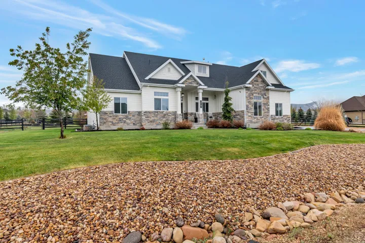 Traditional-style residence featuring a prominent front facade with white siding and stone accents