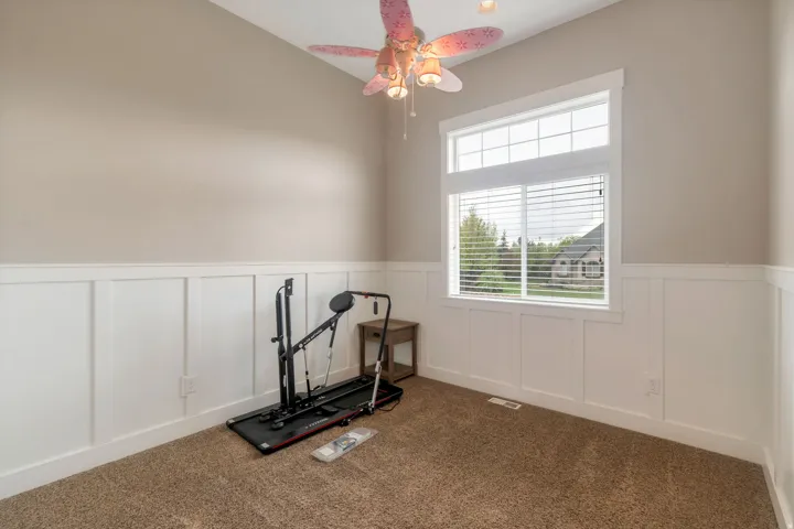 Room featuring board and batten wainscoting, neutral tone walls, and vaulted ceilings