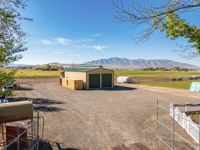 Expansive gravel driveway leading to a metal-sided outbuilding with two roll-up garage doors
