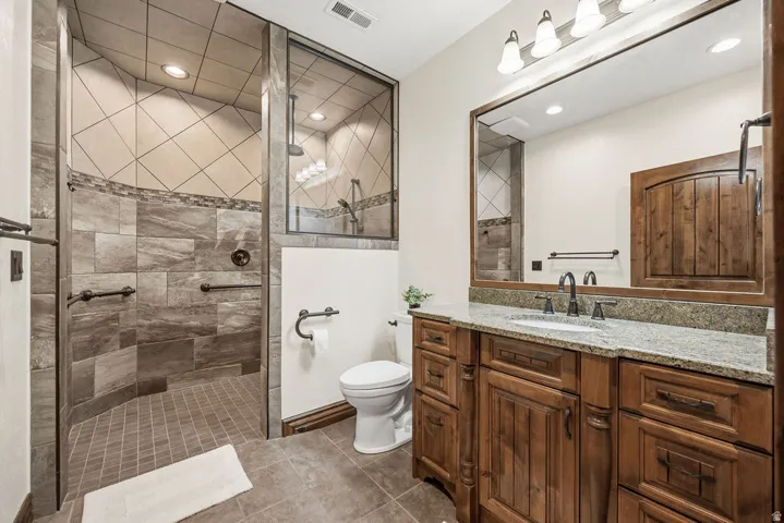 Spacious bathroom featuring a large walk-in shower with glass enclosure and varied tile patterns