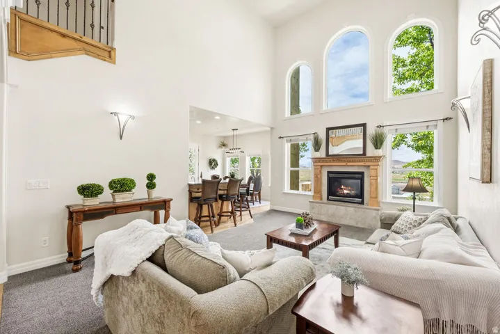 Two-story living area featuring a stone-surround fireplace with a wood mantle, high arched windows, and wood-finish flooring
