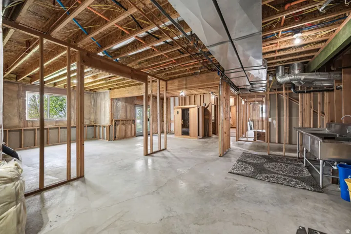 Unfinished basement featuring exposed wood framing, concrete flooring, and an integrated sauna unit