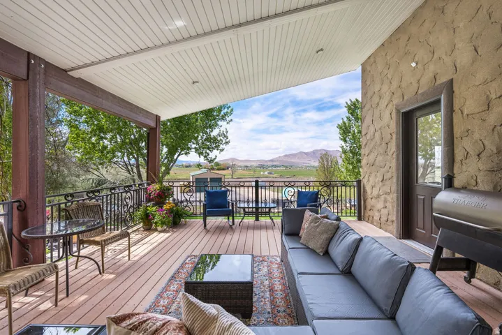 Spacious covered deck featuring composite decking and an ornate black metal railing