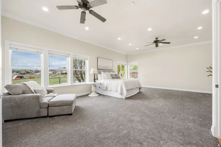 Spacious Primary bedroom featuring broadloom carpet, multiple windows, recessed lighting, and dual ceiling fans