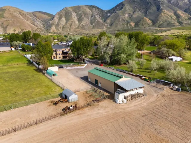 Expansive property featuring a large metal building with a green roof, a separate stable structure, and fenced paddocks