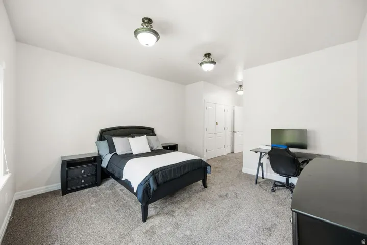 Spacious room featuring neutral carpeting, white painted walls, and two bi-fold closet doors