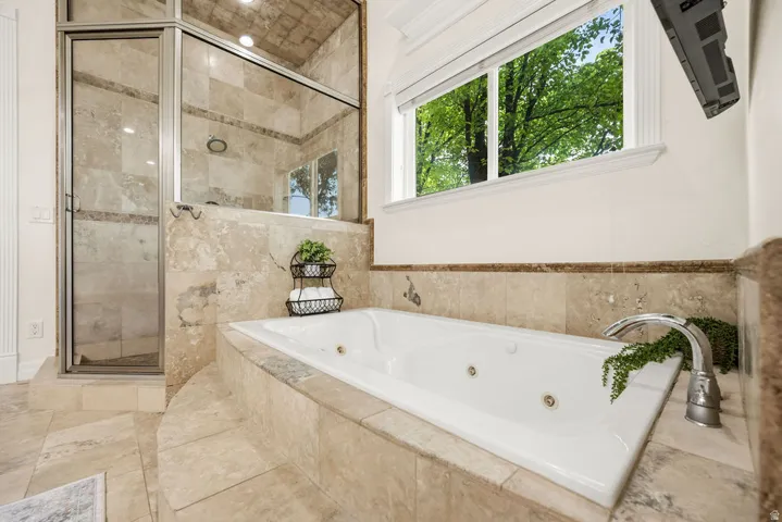 Primary Bath Soaking tub with jetted features set in a tiled surround, complemented by a glass-enclosed shower with matching tile