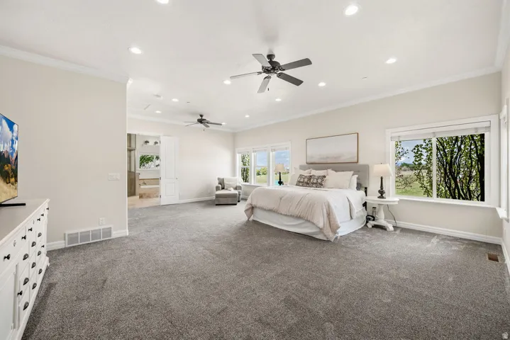 Spacious Primary bedroom featuring plush gray carpeting and white crown molding
