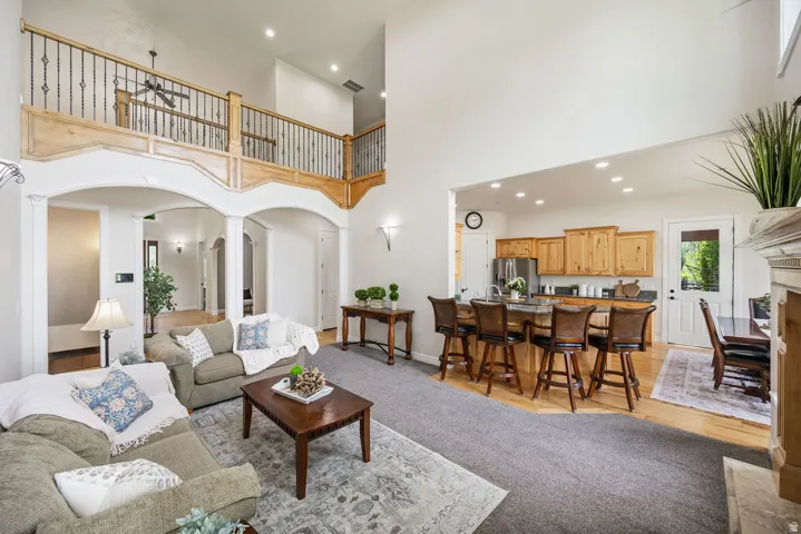 Open-concept living space featuring high ceilings and a second-story balcony with decorative iron railing