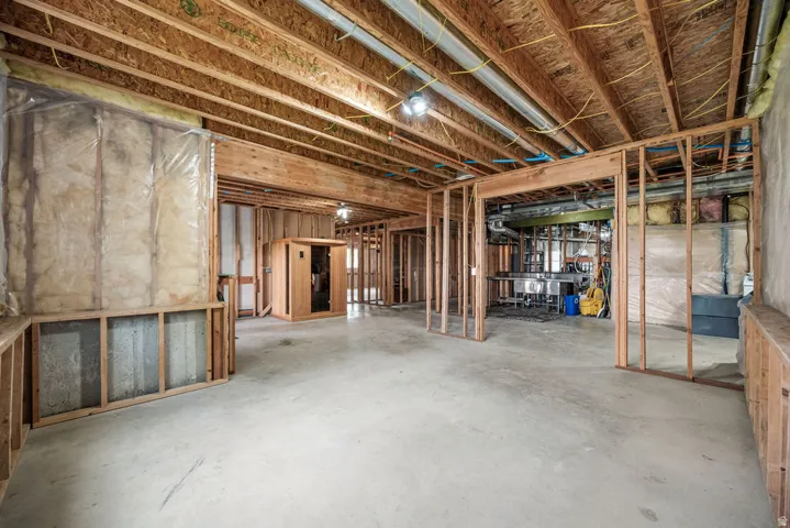 Unfinished basement presenting framed walls, exposed ceiling joists, concrete flooring, and a built-in wooden sauna