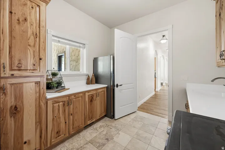 Butler Pantry area featuring wood cabinetry, white countertops, a stainless steel refrigerator, and tiled flooring
