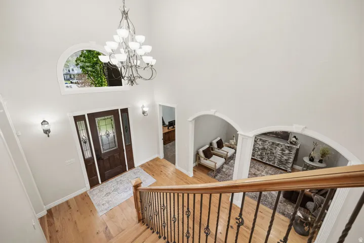 Two-story foyer featuring hardwood flooring, a dark wood entry door with decorative glass inserts and side lites, and a prominent arched transom window