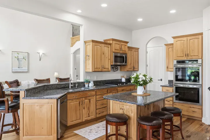 Open-concept kitchen featuring wood-finish cabinetry, granite countertops, and stainless steel appliances