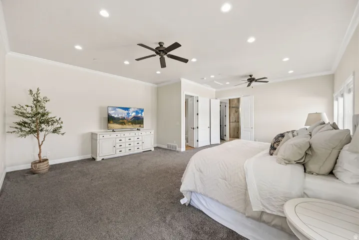 Spacious Primary  bedroom featuring neutral carpeting, crown molding, recessed lighting, and dual ceiling fans