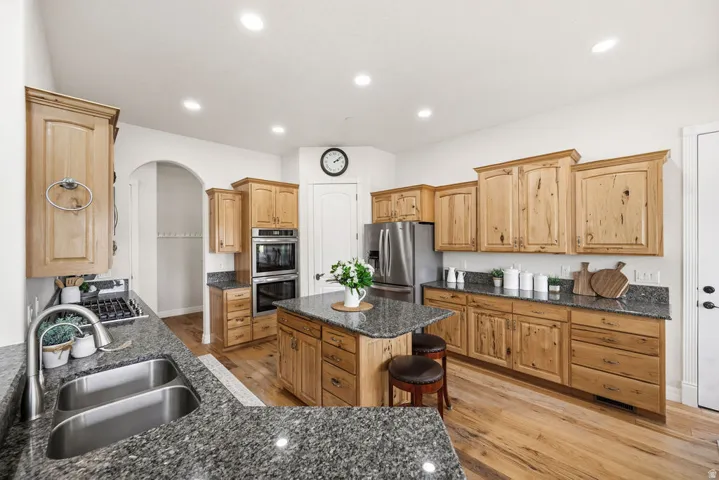 Kitchen featuring wood cabinetry, granite countertops, a stainless steel double basin sink, and built-in double ovens