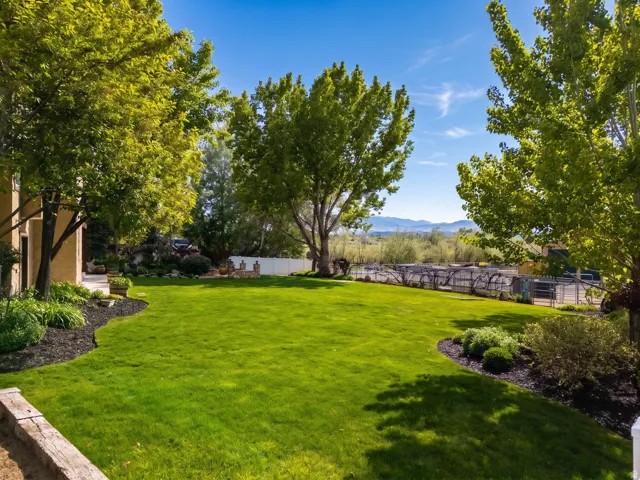 Expansive green lawn with mature trees and landscaped planting beds