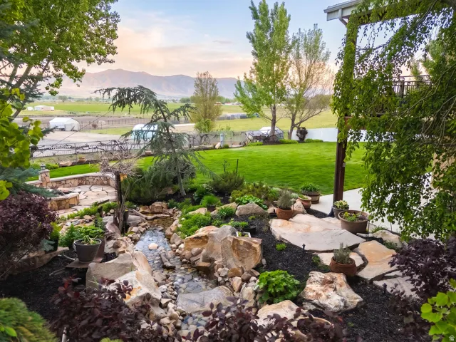 Expansive tiered landscaping featuring a rock-lined stream, diverse plantings, and flagstone pathways
