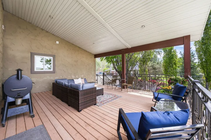 Covered outdoor deck featuring wood-finish flooring and a stucco wall