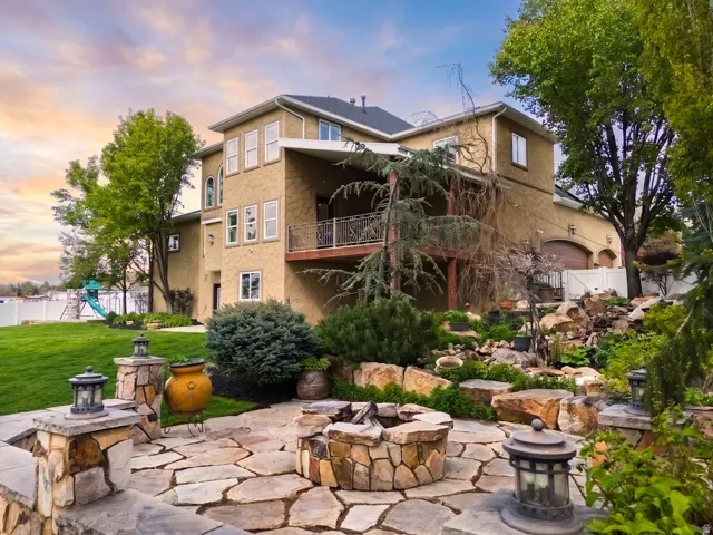 Flagstone patio featuring a built-in stone fire pit, surrounded by tiered landscaping with natural rock elements and mature greenery