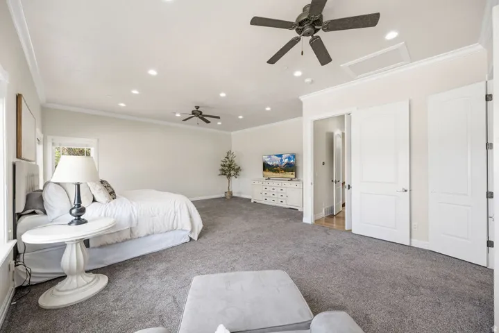 Primary bedroom featuring plush grey carpeting, recessed lighting, and a vaulted ceiling