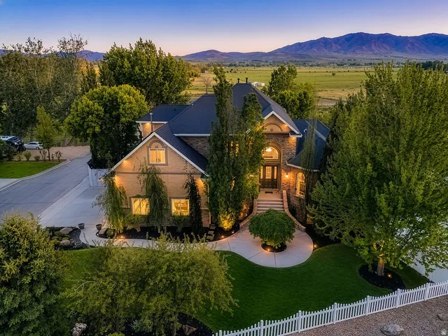 Stately residence featuring a stone and stucco exterior with a dark roof