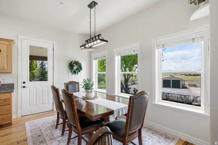 Bright dining area featuring multiple windows, a rear exterior door with glass insert, wood-finish flooring, and a contemporary linear chandelier