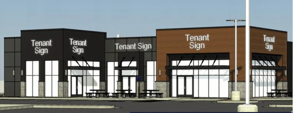 Modern commercial building featuring multiple storefronts with large glass windows and prominent tenant sign areas