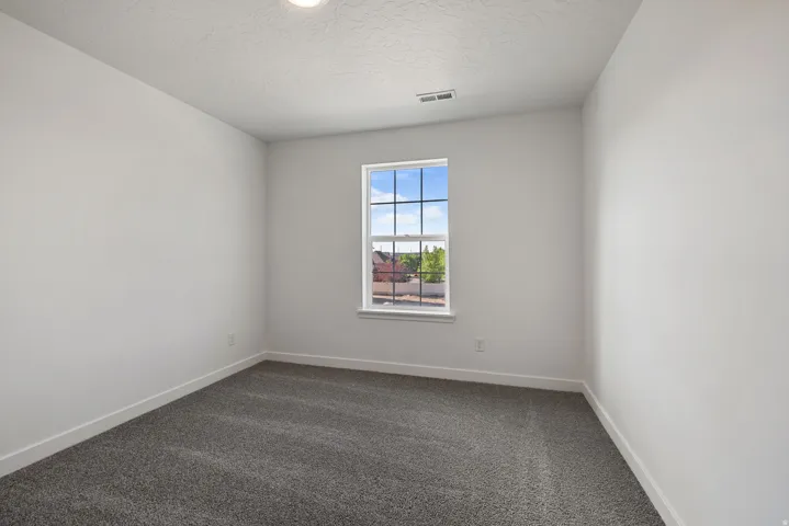 Spacious interior room featuring light gray carpeting, white walls, and bright overhead lighting