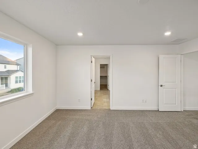 Carpeted room with white walls, recessed lighting, and a white-trimmed window